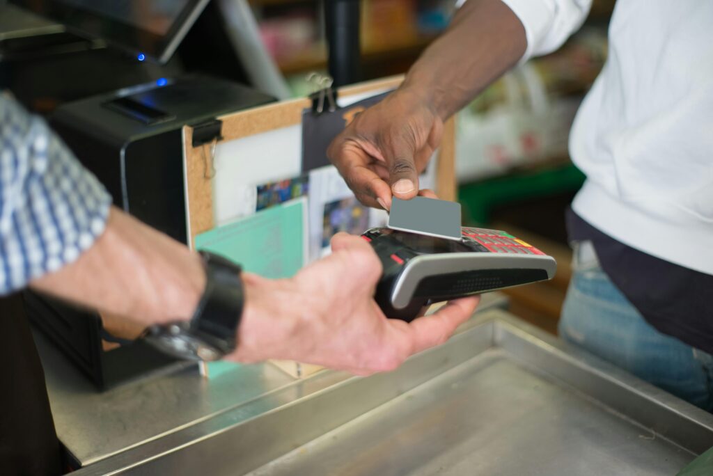 Customer tapping a bank card on a handheld payment terminal at a store checkout