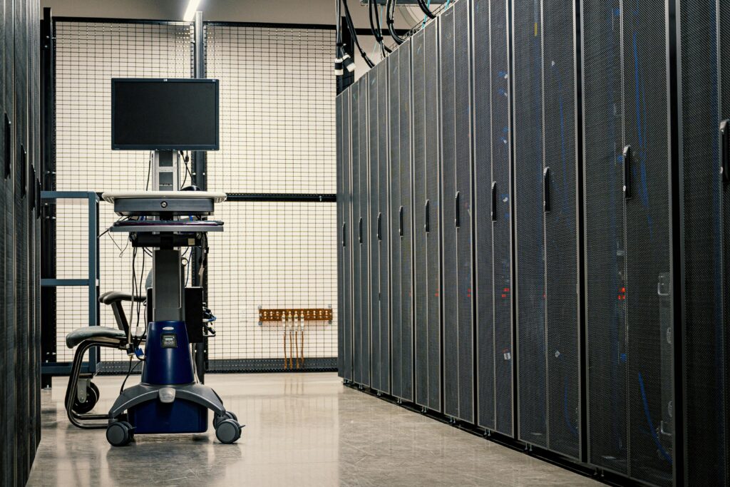 Rows of server racks in a data center aisle with a monitor cart