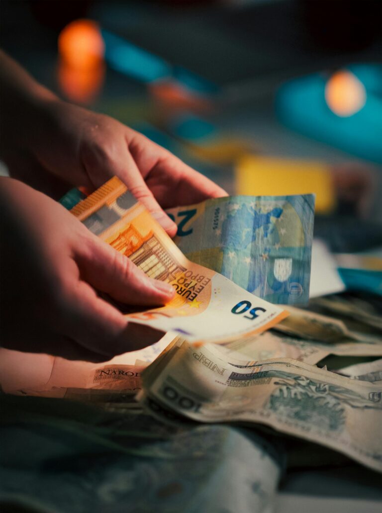 Hands counting euro banknotes over a pile of mixed currency notes