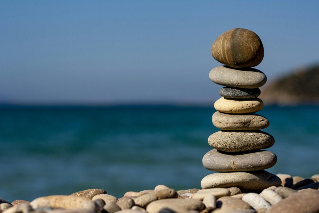 Stack of smooth pebbles balanced on a beach against a blue sea