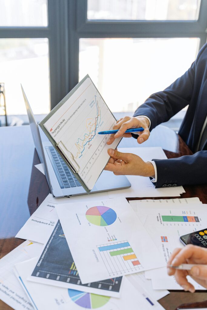 Advisors in suits reviewing financial charts on a clipboard beside a laptop
