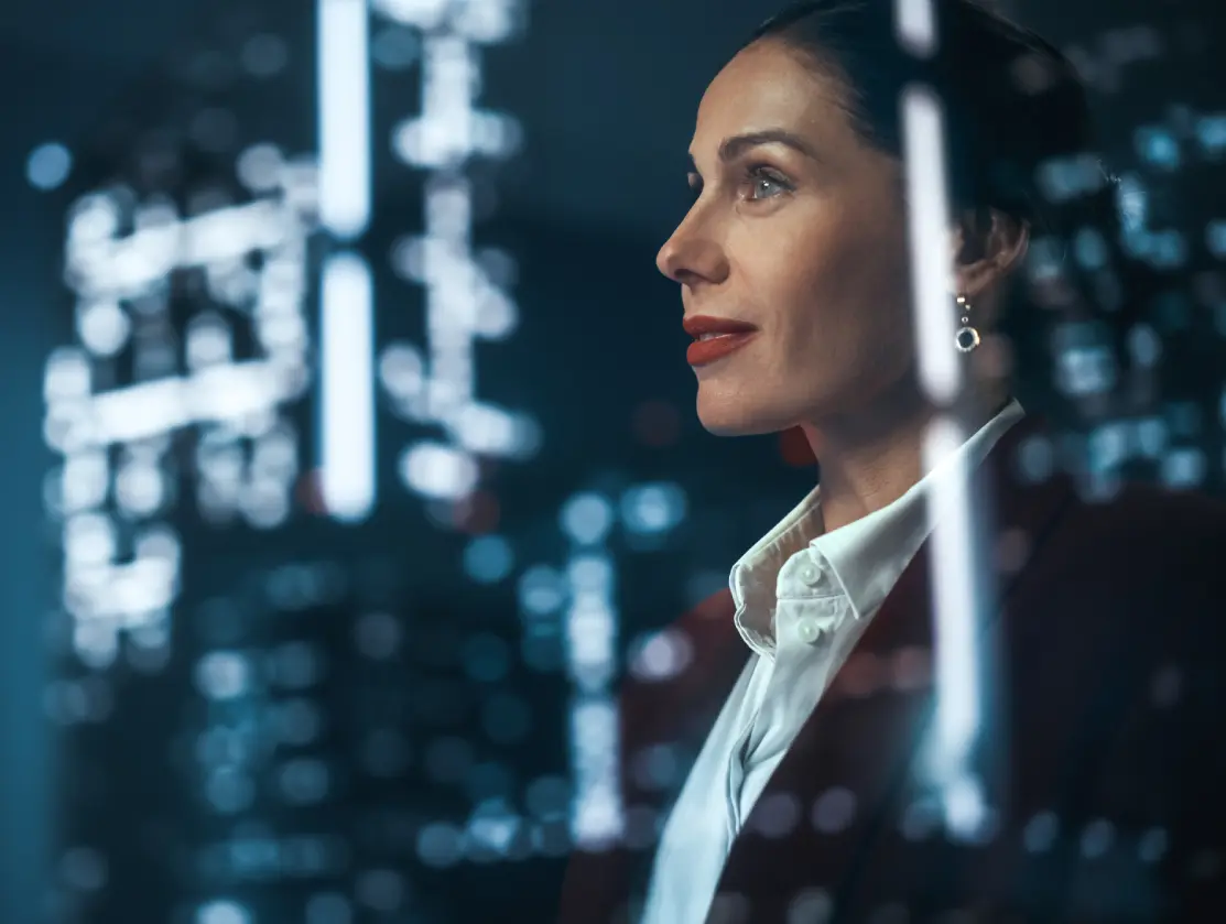 Businesswoman gazing at glowing market data reflected on glass at night