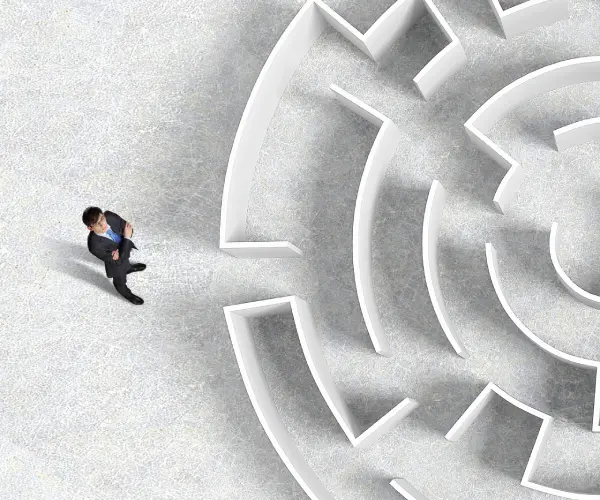 Businessman standing at the entrance of a circular maze viewed from above