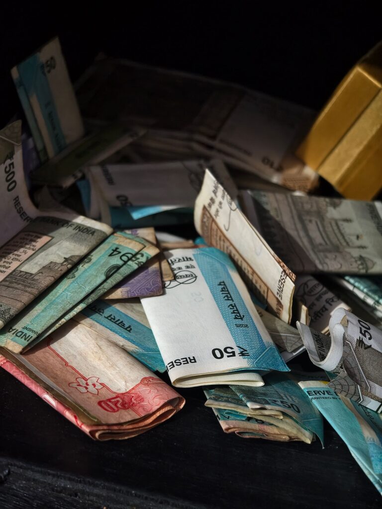 Pile of worn, folded rupee banknotes on a dark surface
