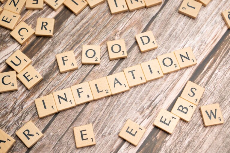 Scrabble tiles spelling food and inflation on a wooden table
